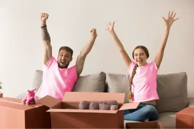 Un couple exulte sur le canapé entre les cartons de déménagement