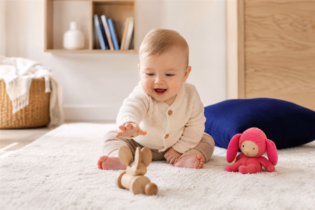 Baby sitzt auf dem Teppich und spielt mit Holzspielzeug