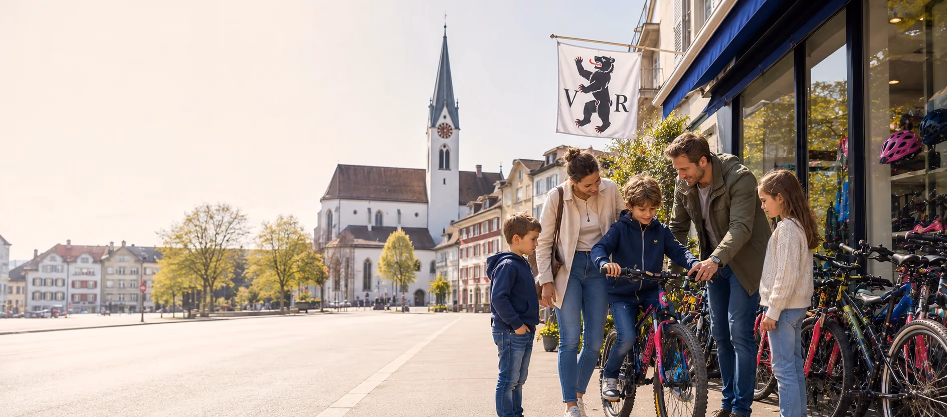Familie vor einem Veloladen auf einem Platz in Appenzell Ausserrhoden, im Hintergrund eine Kirche
