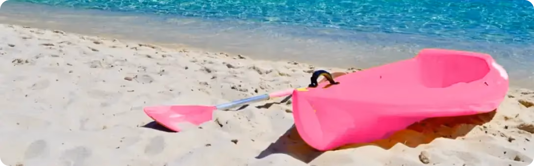 Roze kajak sa veslom na peščanoj plaži