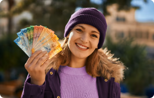 Donna sorridente con il berretto che tiene un ventaglio di banconote