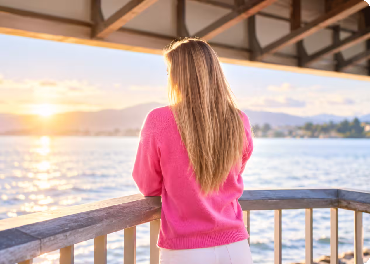 Una donna con giacca di jeans rosa guarda l'acqua dalla ringhiera