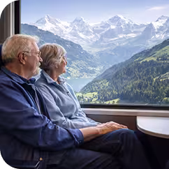 Älteres Ehepaar reist im Zug durch die Schweizter Bergwelt und schaut zum Fenster hinaus